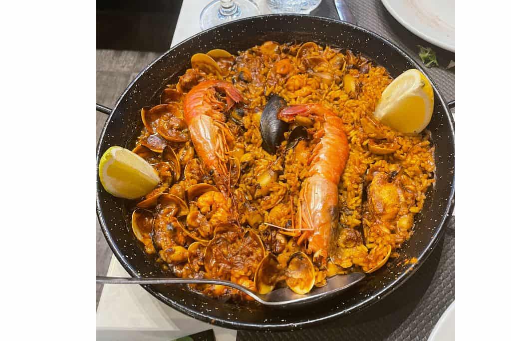 plate of paella with seafood and lemon wedges