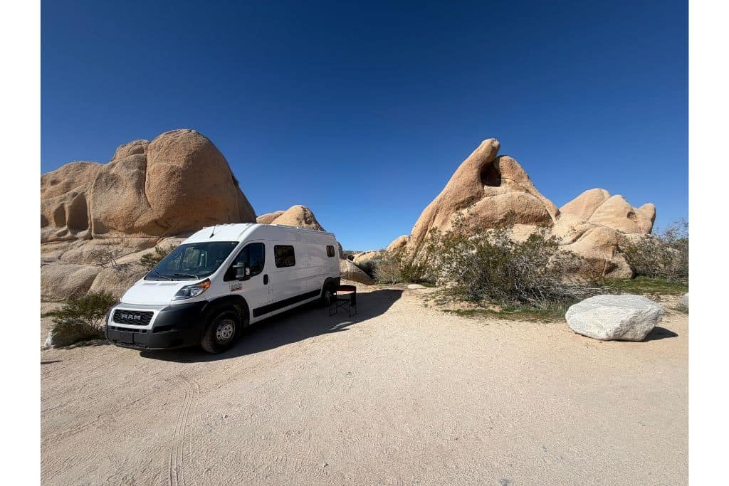 Van parked in campsite between rock formations Joshua Tree National Park